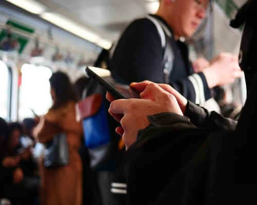 A commuter standing inside train holding phone
